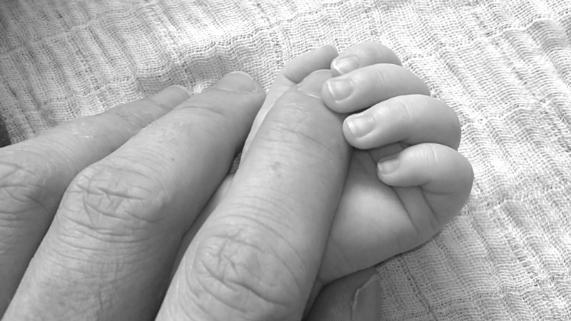 black-and-white-image-of-man-holding-babys-fingers
